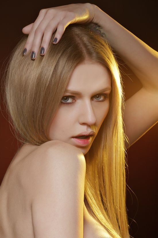 Close-up editorial beauty portrait of Simona featuring warm studio lighting and expressive posing