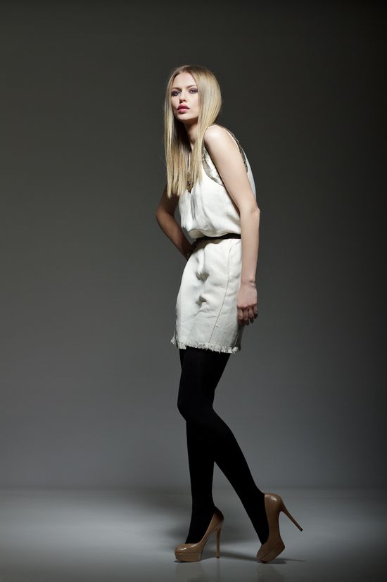 Full-length fashion portrait of Simona wearing a minimalist white dress, black tights, and high heels