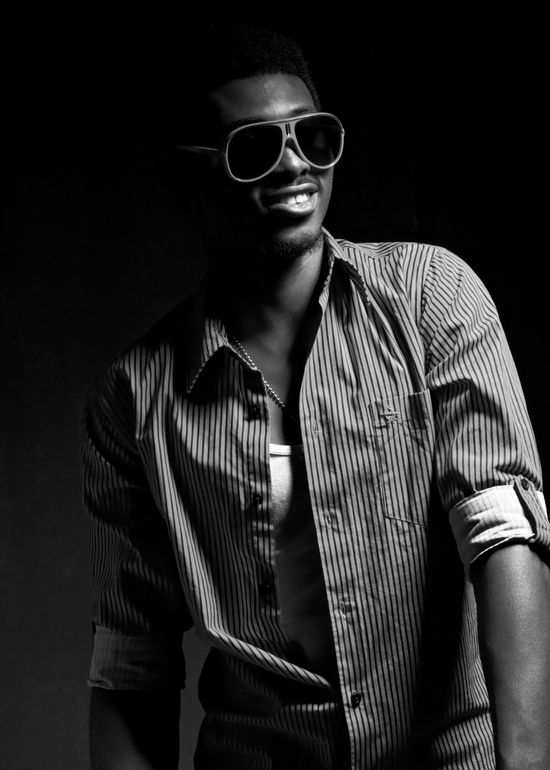Low-key black and white portrait of Josh smiling while wearing sunglasses and a striped shirt.