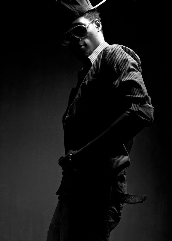 Dramatic black and white fashion portrait of Josh posing in silhouette with rim lighting against a dark background.